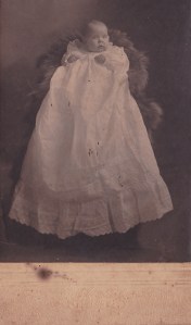 Detail of card photograph of Beth Wolf (or Half) in christening gown, made by Mr. & Mrs. Persons, Dublin GA ca. 1910